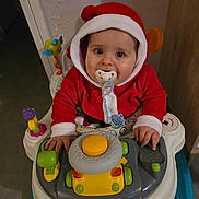 Myllan participe au concours pour gagner de l'argent avec cette photo : baby, blue_eyes, child, christmas, cute, expression, face, hands, holiday, indoor, infant, pacifier, person, playful, red_clothing, santa_outfit, seat, toy, walker, young_child