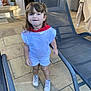 bench, blue_eyes, casual, child, curly_hair, daylight, lounge_chair, outdoor, patio, playful, potted_plant, red_scarf, shorts, smiling, sneakers, standing, statue, stone_floor, toddler, white_clothing