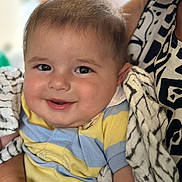 Alex is registered to the contest to win money with this photo: baby, smiling, child, blanket, striped_shirt, person, face, cheeks, arm, holding, patterned_clothing, adult, close_up, indoor, soft_light, happy, cute, portrait, infant, comfort