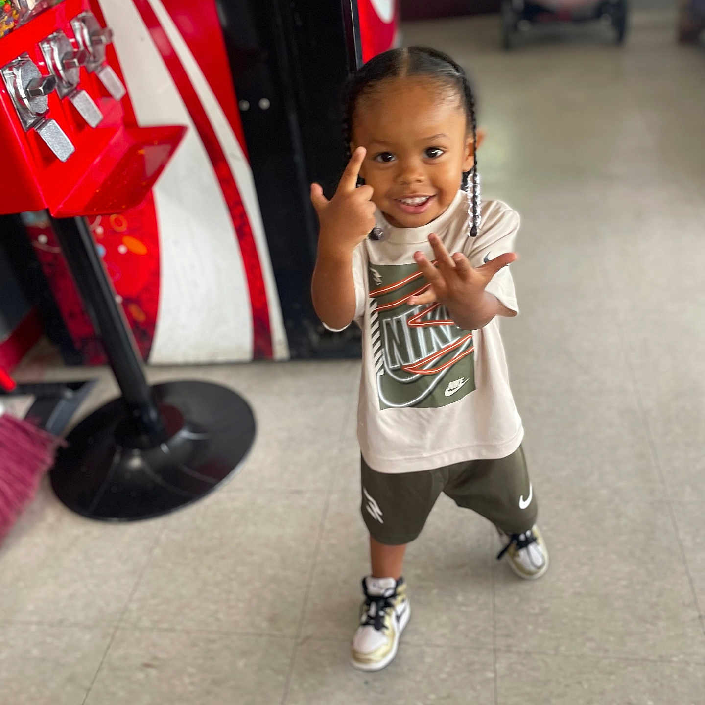 Keyontae is registered to the contest to win money with this photo: braids, candy_dispenser, casual_wear, child, clothing, floor, footwear, happy, indoor, nike, person, playful, portrait, retail, smiling, sneakers, standing, stroller, tiled_floor, young_child
