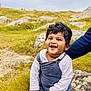Luka joined the competition — help win amazing prizes! toddler, child, smiling, outdoor, grass, rock, nature, happy, person, curly_hair, field, daylight, casual_clothing, supporting_hand, white_shirt, blue_overalls, portrait, baby, young_child, cheerful