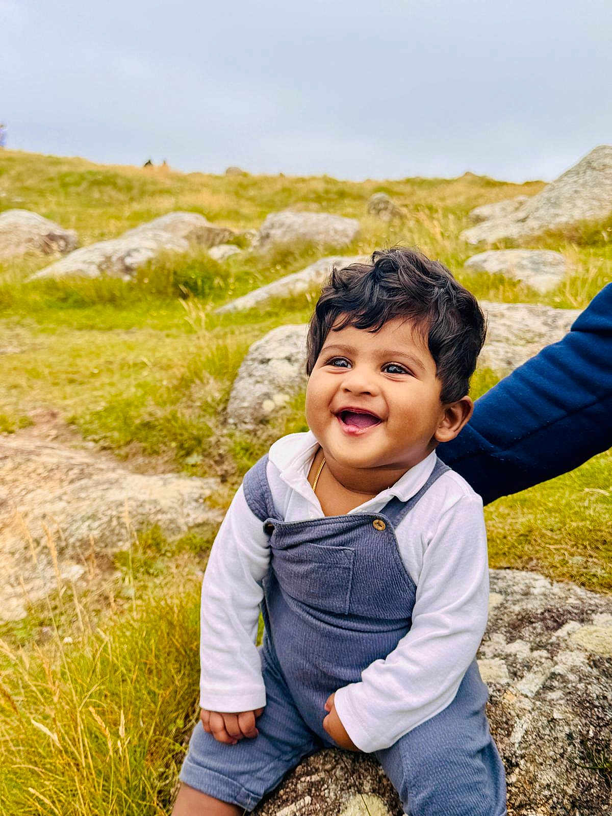 Luka joined the competition — help win amazing prizes! toddler, child, smiling, outdoor, grass, rock, nature, happy, person, curly_hair, field, daylight, casual_clothing, supporting_hand, white_shirt, blue_overalls, portrait, baby, young_child, cheerful