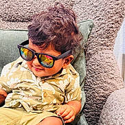 Luka joined the competition — help win amazing prizes! toddler, child, sunglasses, shirt, shorts, chair, cushion, indoors, smile, hair, skin, foot, hand, texture, pattern, casual, relaxed, reflection, comfort, fashion