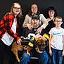 Bear is registered to the contest to win money with this photo: family, group, dog, pet, people, smiling, glasses, beard, black_background, casual_clothing, sports_jersey, seated, standing, indoor, portrait, happy, young, adult, child, leather_cap