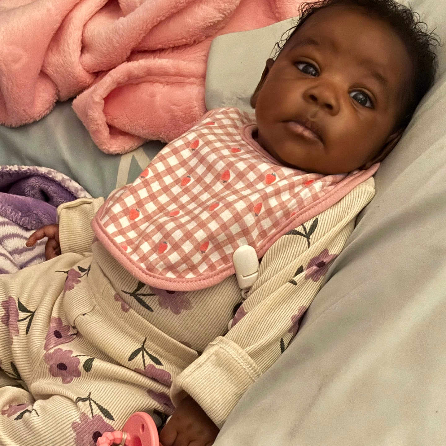 Leilani is registered to the contest to win money with this photo: baby, blanket, child, comfort, cozy, cute, face, floral_pajamas, indoors, infant, lying_down, pacifier, pink_bib, portrait, relaxed, resting, skin, sleepwear, soft_texture, young_child
