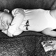 Léo participe au concours pour gagner de l'argent avec cette photo : baby, sleeping, blanket, onesie, infant, peaceful, texture, fabric, foot, hand, face, couch, cozy, rest, black_and_white, portrait, cute, child, soft, relaxation