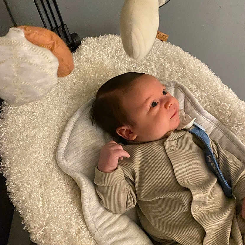 Menzio a rejoint le concours — aidez-le/la à gagner de superbes lots ! baby, baby_bed, blanket, child, clothing, comfort, curious, cushion, cute, face, indoor, infant, newborn, onesie, person, plush_toys, relaxed, resting, sleeping_bed, soft_texture