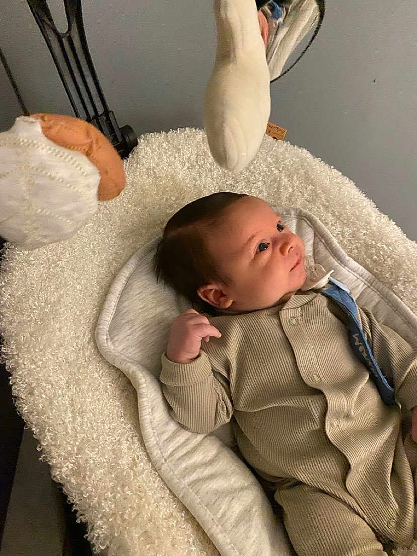 Menzio a rejoint le concours — aidez-le/la à gagner de superbes lots ! baby, infant, onesie, plush_toys, cushion, soft_texture, indoor, child, sleeping_bed, newborn, cute, face, person, clothing, comfort, resting, curious, baby_bed, blanket, relaxed