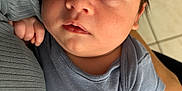 Menzio participe au concours pour gagner de l'argent avec cette photo : arm, baby, blue_clothing, caring, child, closeup, curious, face, floor, hand, holding, indoor, infant, newborn, onesie, person, portrait, skin, soft_lighting, tile