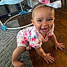 baby, child, crawling, floor, wooden_floor, rug, baby_walker, headband, bow, smiling, happy, indoor, clothing, pink, blue, floral_pattern, person, infant, cute, home