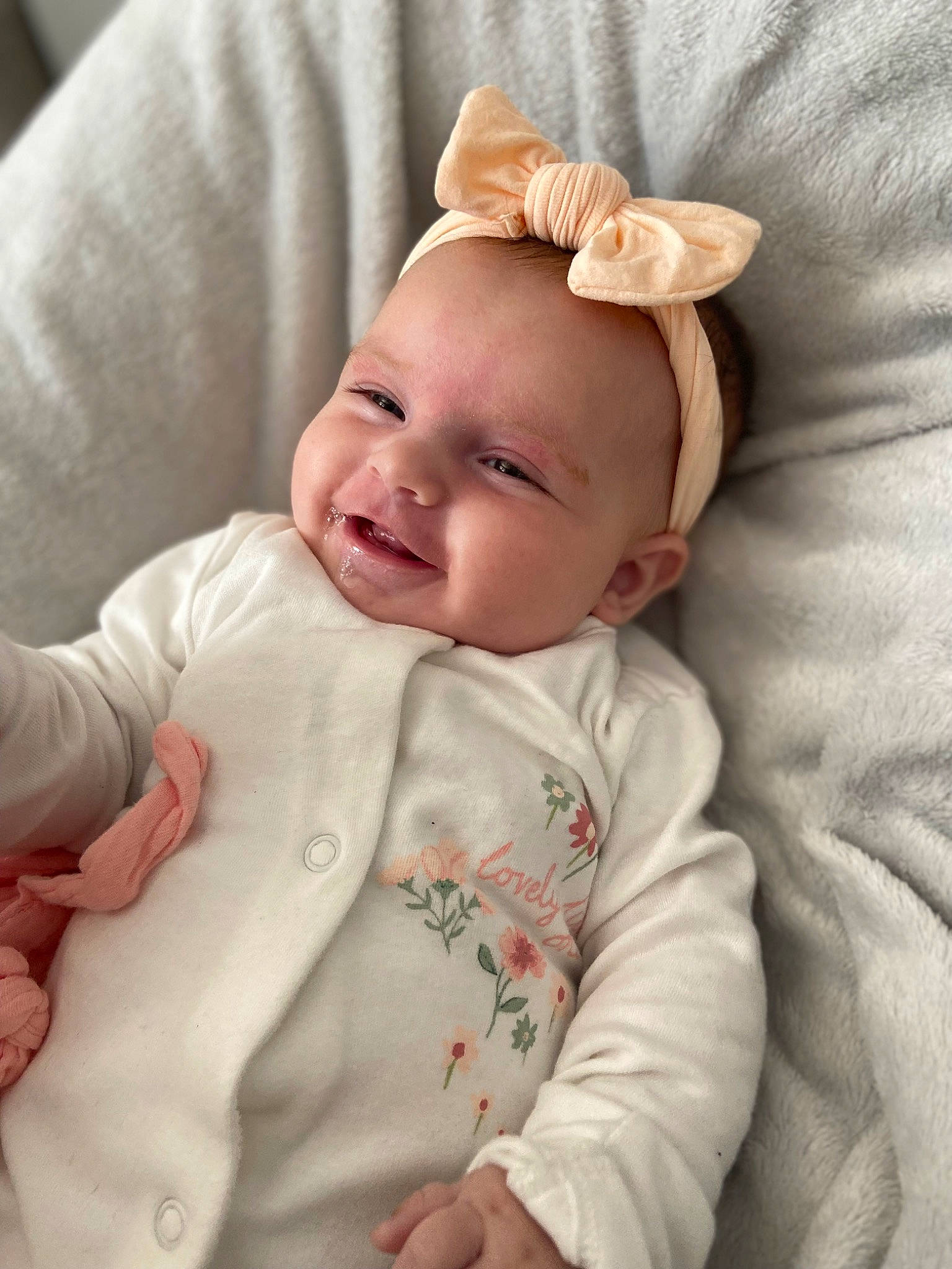 Amelie is registered to the contest to win money with this photo: baby, baby_toddler_clothing, child, collar, comfort, face, happy, linens, pattern, peach, person, pink, portrait_photography, skin, sleeve, smile, textile, toddler