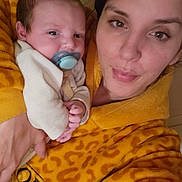 Elesyo participe au concours pour gagner de l'argent avec cette photo : baby, pacifier, adult, person, robe, yellow, leopard_print, holding, face, portrait, indoor, cozy, warm_clothing, expression, closeup, skin, hand, looking_at_camera, newborn, family