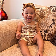 Ari joined the competition — help win amazing prizes! baby, child, smiling, sitting, couch, headband, striped_clothing, happy, indoor, furniture, infant, portrait, cute, toddler, apparel, living_room, fabric, decor, comfort, skin