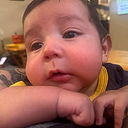 Ares joined the competition — help win amazing prizes! baby, face, arm, tattoo, indoor, blurred_background, child, closeup, expression, skin, person, furniture, television, resting, cute, young_child, casual_clothing, portrait, chubby_cheeks, hands