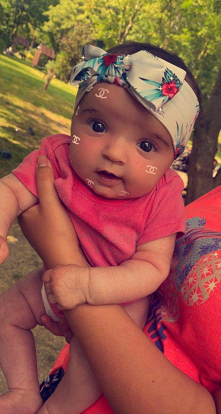 Lilia a rejoint le concours — aidez-le/la à gagner de superbes lots ! baby, baby_toddler_clothing, black_hair, cap, child, facial_expression, fun, grass, happy, hat, headwear, human_body, leisure, neck, people_in_nature, person, pink, plant, skin, standing