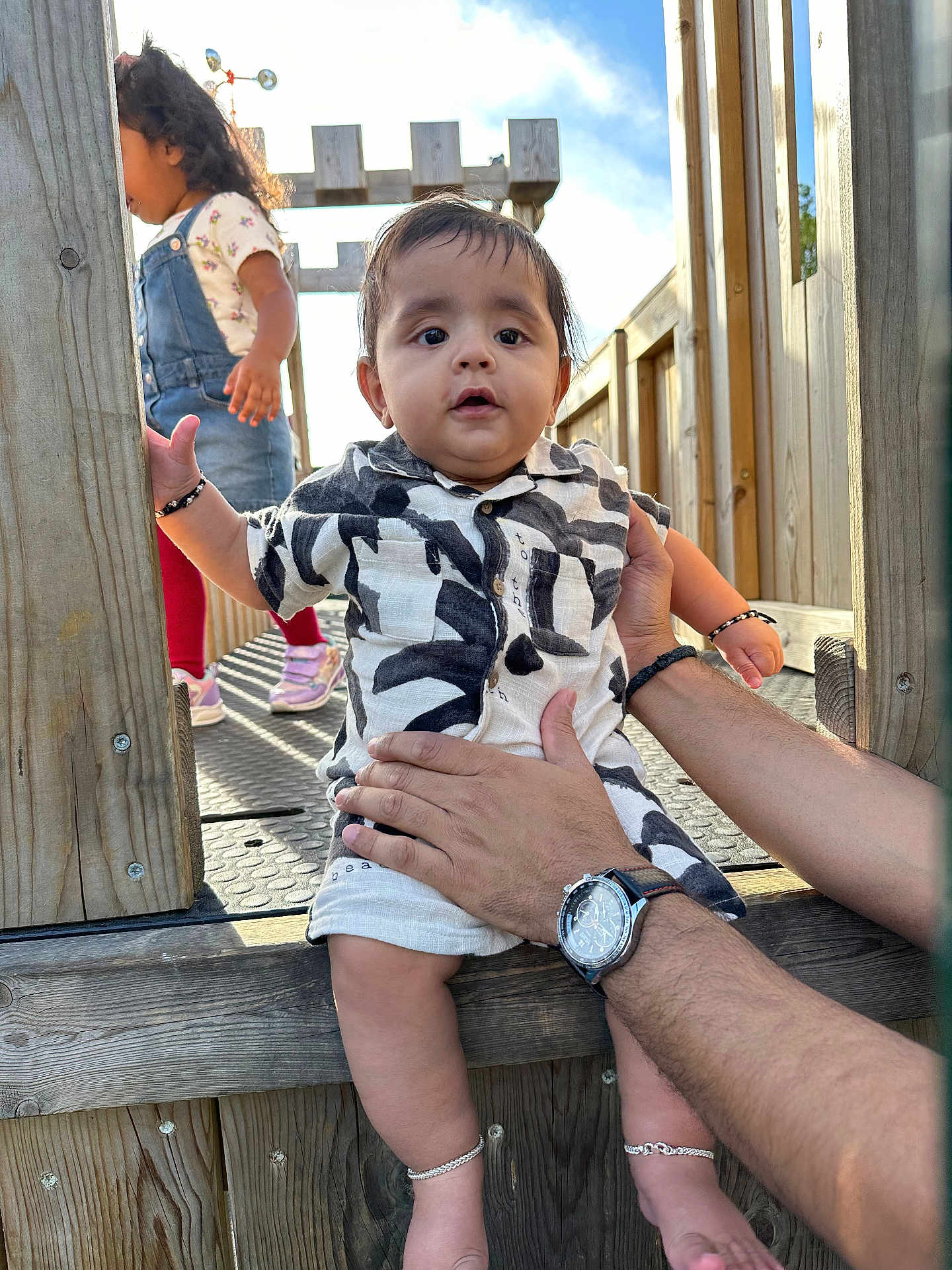 Daivik joined the competition — help win amazing prizes! baby, child, person, hands, playground, wood, romper, bracelet, anklet, watch, outdoor, sunlight, sky, overalls, sneakers, red_tights, walking, play_structure, daylight, cute
