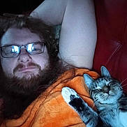 Rowdy joined the competition — help win amazing prizes! man, beard, glasses, cat, tabby_cat, orange_blanket, couch, red_couch, relaxing, indoor, smiling_cat, paw, feline, facial_hair, curly_hair, resting, closeup, pet, companion, casual
