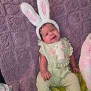 Harper joined the competition — help win amazing prizes! baby, bunny_ears, smiling, green_outfit, blanket, purple_blanket, soft_toys, cute, infant, child, happy, indoors, person, plush, costume, headwear, sitting, cozy, texture, playful