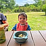 Mathéo participe au concours pour gagner de l'argent avec cette photo : baby, bib, bowl, child, clouds, daylight, denim, greenery, happy, nature, outdoor, person, portrait, sippy_cup, sky, smile, snack, table, toddler, wooden_table