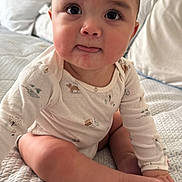 Emiliano is registered to the contest to win money with this photo: baby, infant, child, onesie, bed, blanket, pillow, tongue, cute, skin, face, eyes, hand, foot, sitting, indoors, soft_lighting, expression, portrait, home