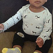 Dominic joined the competition — help win amazing prizes! child, toddler, sitting, sofa, couch, onesie, dog_print, football_motif, socks, striped_socks, hands, legs, face, eyes, eyebrows, neutral_expression, indoor, home, carpet, soft_lighting