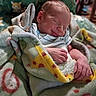 newborn, baby, sleeping, infant, portrait, blanket, swaddled, cozy, peaceful, indoors, bed, textile, patterned, colorful, hand, face, closed_eyes, cuddled, nursery, photography