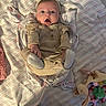 baby, infant, blanket, striped_blanket, headband, surprised_expression, soft_toys, beige_outfit, lying_down, indoor, cute, child, person, footwear, pajamas, fabric, playtime, happy, small_hands, newborn