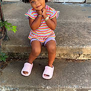 Alanna joined the competition — help win amazing prizes! child, girl, pigtails, smile, concrete, steps, door, screen_door, bracelet, slippers, colorful_clothing, outdoor, pose, cute, happy, young_child, casual, sitting, playful, portrait