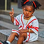 Alanna joined the competition — help win amazing prizes! child, girl, curly_hair, pigtails, red_bows, white_shirt, red_stripes, gold_chain, bracelets, sneakers, sitting, stone_ledge, outdoor, serious_expression, finger_raised, cute, fashion, portrait, youth, casual