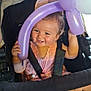 baby, stroller, balloon, purple_balloon, smiling, child, hat, indoor, seatbelt, happy, cute, infant, clothing, person, hands, face, legs, playful, toddler, toy