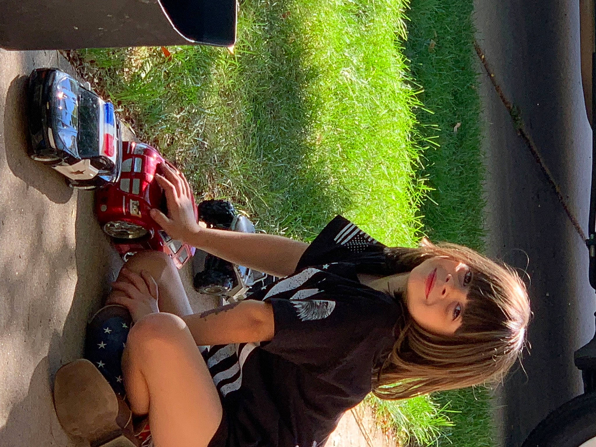 Sophia joined the competition — help win amazing prizes! auto_part, automotive_exterior, automotive_lighting, eyewear, fun, grass, helmet, human_leg, joy, knee, landscape, leg, leisure, luggage_and_bags, person, personal_protective_equipment, recreation, sandal, shorts, sitting