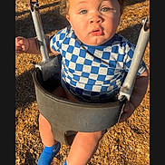 Zaylin is registered to the contest to win money with this photo: toddler, child, swing, playground, curly_hair, blue_socks, checkered_shirt, sunlight, shadow, woodchips, outdoor, baby, seat, fun, play, daylight, person, young_child, park, casual_clothing
