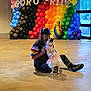 person, dog, balloons, rainbow, pride, costume, indoor, celebration, colorful, sitting, glasses, hat, floor, unicorn, decorations, party, window, casual_clothing, playful, cute