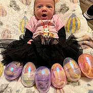Nala joined the competition — help win amazing prizes! baby, infant, child, girl, headband, flower, pink_shirt, bunny_graphic, black_tutu, plastic_eggs, easter_eggs, blanket, patterned_blanket, floor, toy, cute, lying_down, indoors, colorful, smiling