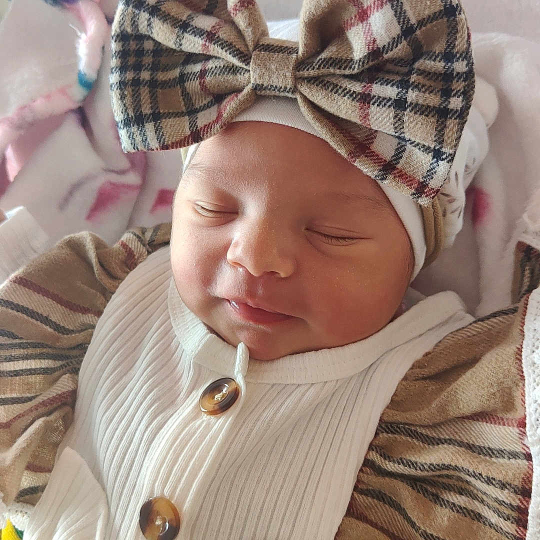 Tiziri participe au concours pour gagner de l'argent avec cette photo : baby, blanket, bow, button, child, clothing, cozy, cute, fabric, face, headwear, infant, newborn, pattern, plaid, portrait, resting, sleeping, smiling, soft