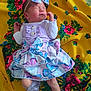 baby, newborn, sleeping, purple_clothing, butterfly_pattern, headband, blanket, yellow, floral, cute, infant, small, peaceful, soft, white_socks, lace, adorable, lying_down, child, portrait