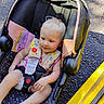 Emery joined the competition — help win amazing prizes! baby, child, car_seat, seatbelt, blonde_hair, outdoor, sunlight, curb, yellow_paint, happy, smiling, infant, clothing, colorful, sitting, person, young_child, safety_harness, road, foot