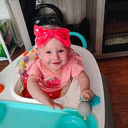 Emery joined the competition — help win amazing prizes! baby, child, cute, face, fireplace, furniture, happy, headwear, high_chair, home, indoor, infant, person, pink_clothing, red_bow, seat, smiling, table, toy, wooden_floor