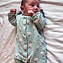 baby, infant, onesie, sleepwear, flower_pattern, blanket, lying_down, newborn, cute, soft_texture, baby_clothes, small_hands, peaceful, resting, portrait, indoors, cozy, child, person, sleepy
