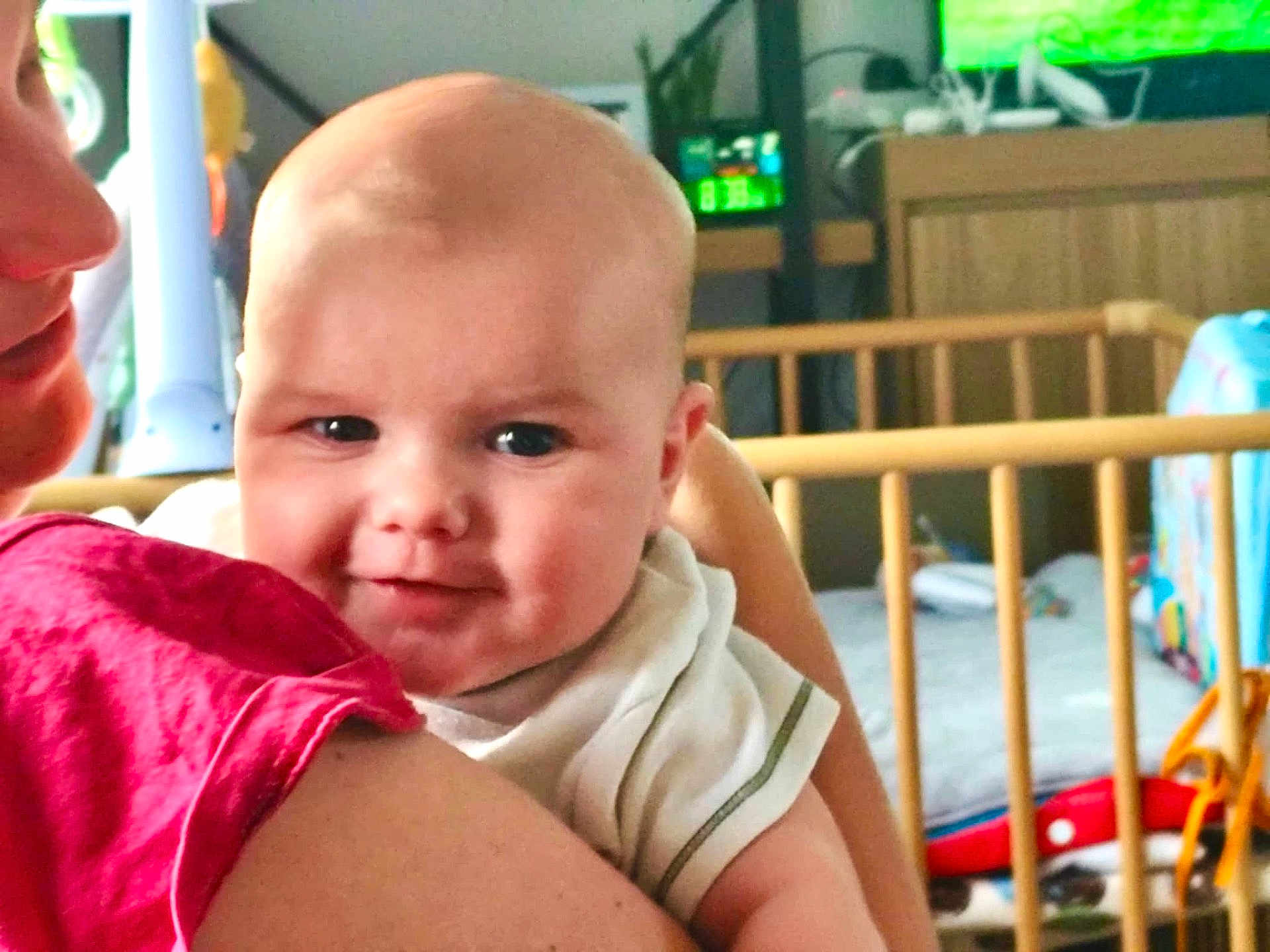 Louka a rejoint le concours — aidez-le/la à gagner de superbes lots ! baby, infant, person, face, smile, arm, clothing, indoor, crib, toy, child, holding, closeup, happy, parent, furniture, home, room, skin, head