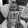 Gabriel is registered to the contest to win money with this photo: baby, black_and_white, blanket, celebration, child, comfort, cushion, cute, flag, fourth_of_july, hand, holiday, infant, monochrome, onesie, person, portrait, sitting, smiling, text