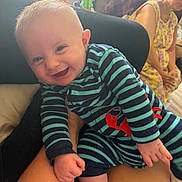 Gabriel joined the competition — help win amazing prizes! adult, baby, couch, face, family, hand, happy, home, indoor, joyful, onesie, person, plant, playful, seated, skin, smiling, striped_clothing, window, woman