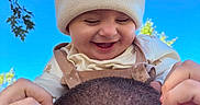 Gabriel is registered to the contest to win money with this photo: adult, baby, beanie, blue_sky, child, hands, head, infant, joyful, knit_hat, laughing, leaves, outdoor, overalls, playful, portrait, shirt, sky, smiling, trees