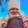 baby, child, infant, smiling, laughing, portrait, outdoor, sky, blue_sky, trees, leaves, beanie, knit_hat, overalls, shirt, hands, adult, head, playful, joyful