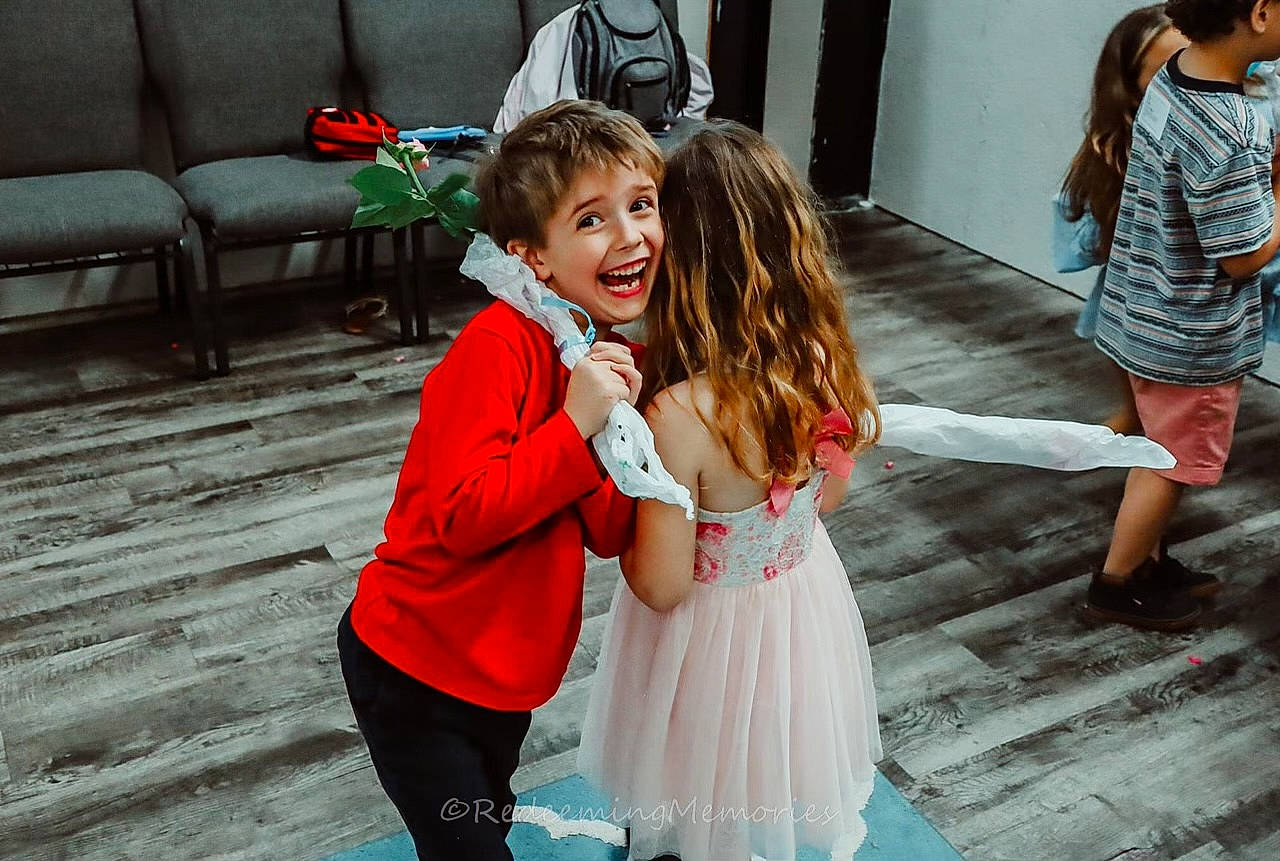 Timothy is registered to the contest to win money with this photo: bridal_clothing, child, clothing, dress, event, flash_photography, formal_wear, friendship, fun, gesture, green, hair, happy, interaction, joy, leisure, person, shoe, skin, smile