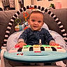 baby, child, toy, piano, play, smile, couch, living_room, onesie, hanging_toys, cushion, furniture, indoors, person, happy, photography, portrait, infant, home, cute