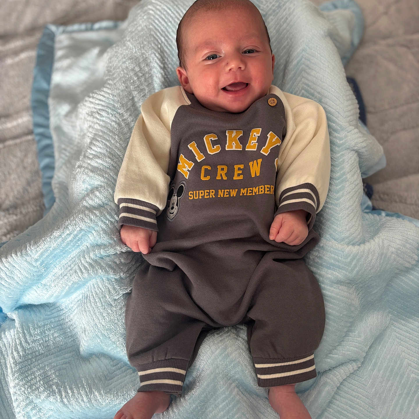 Oakley joined the competition — help win amazing prizes! baby, bedroom, blanket, blue_blanket, clothing, cozy, cute, face, feet, hands, happy, indoors, infant, lying_down, mickey_mouse, newborn, onesie, portrait, smiling, soft_texture