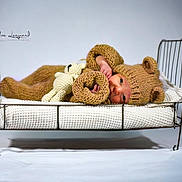 Gabin participe au concours pour gagner de l'argent avec cette photo : baby, infant, knitted_outfit, bear_ears, crocheted_toy, bed, metal_frame, blanket, lying_down, cute, cozy, portrait, studio, soft_lighting, child, newborn, warm_colors, sleepwear, small_bed, adorable