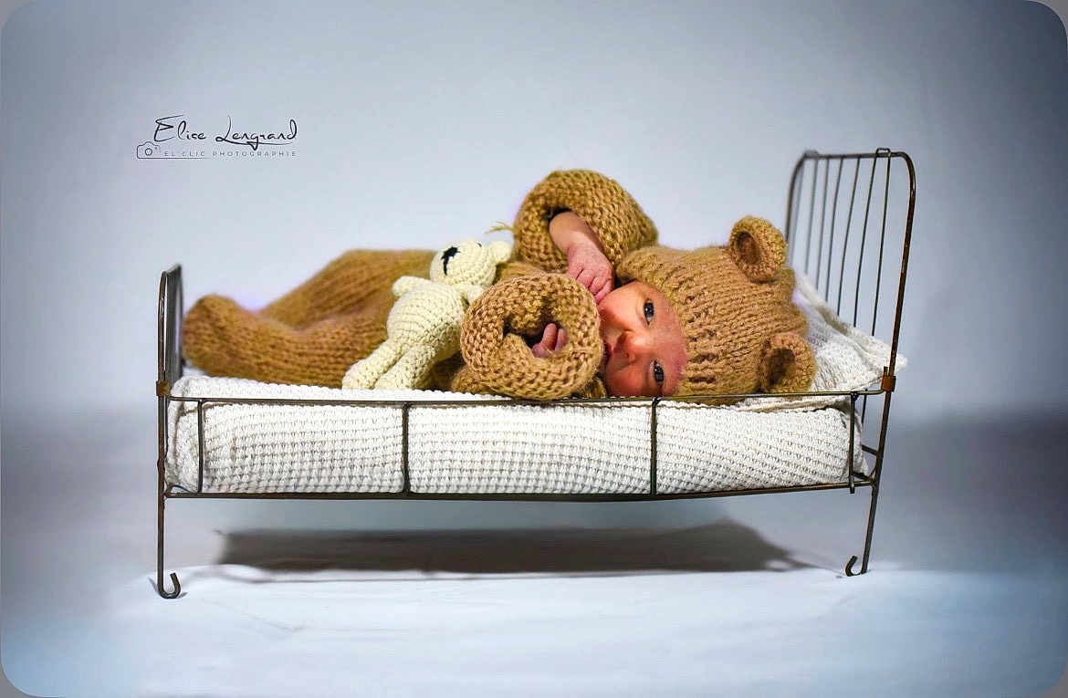 Gabin participe au concours pour gagner de l'argent avec cette photo : baby, infant, knitted_outfit, bear_ears, crocheted_toy, bed, metal_frame, blanket, lying_down, cute, cozy, portrait, studio, soft_lighting, child, newborn, warm_colors, sleepwear, small_bed, adorable