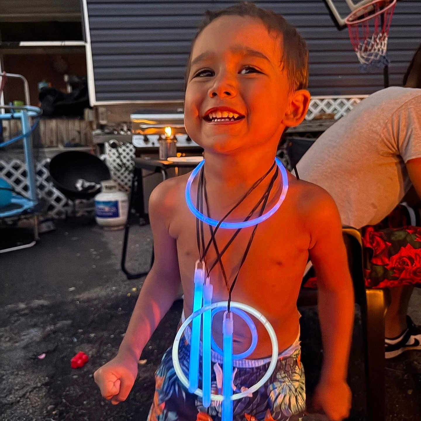 Braylen Yates is registered to the contest to win money with this photo: backyard, basketball_hoop, boy, child, evening, fun, furniture, glow_sticks, happy, joy, light, necklaces, outdoor, patio, person, playful, shirtless, shorts, smiling, summer